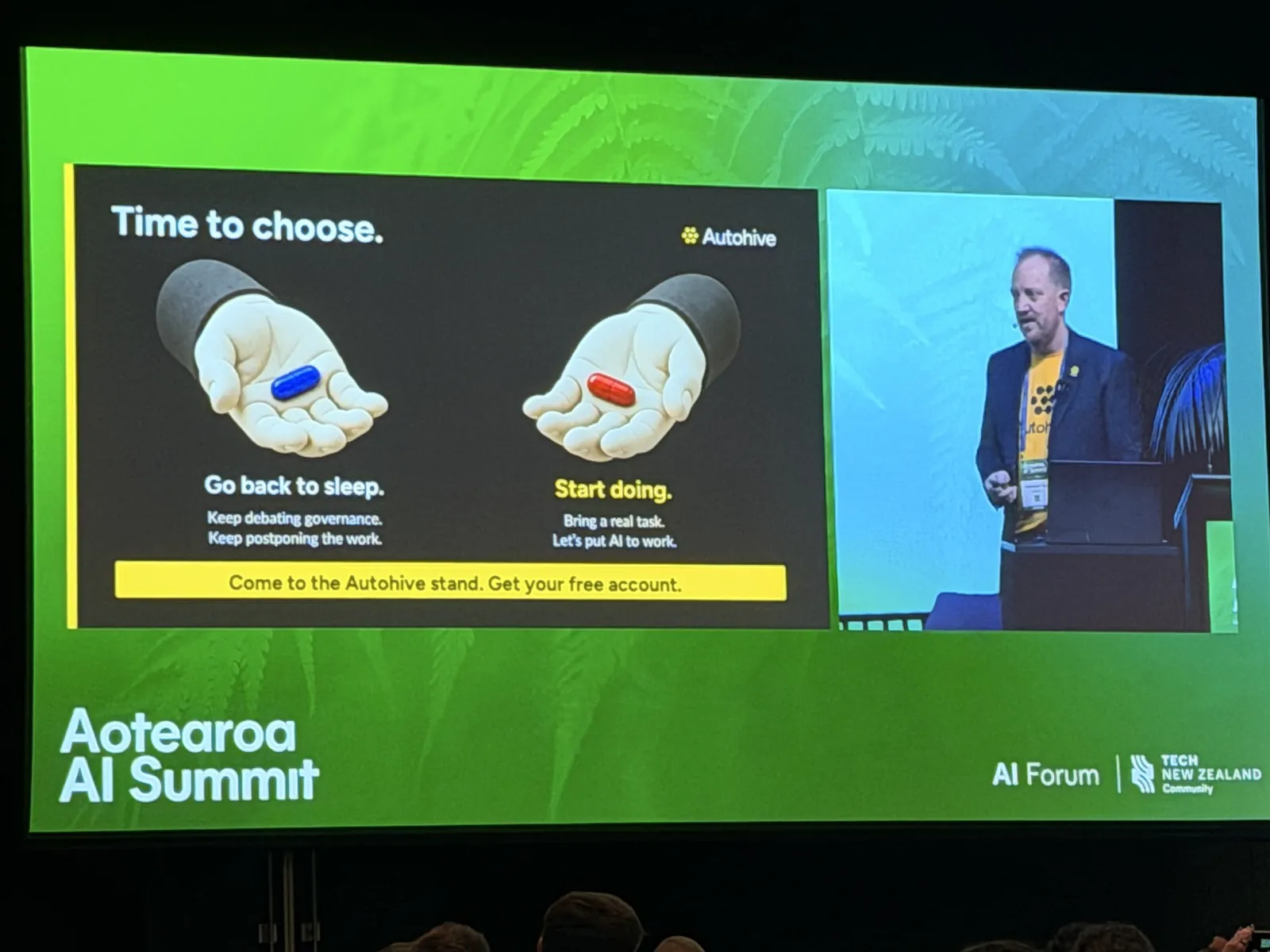 The summit screen showing an Autohive keynote slide titled Time to choose, with a blue pill labelled Go back to sleep and a red pill labelled Start doing