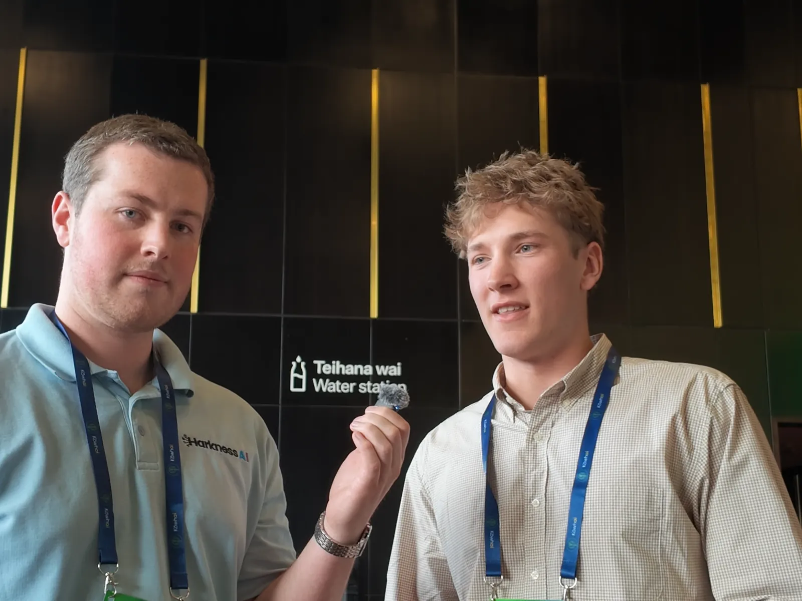 Ed Davidson standing beside Blake Harkness in front of a sign reading Teihana wai, Water station