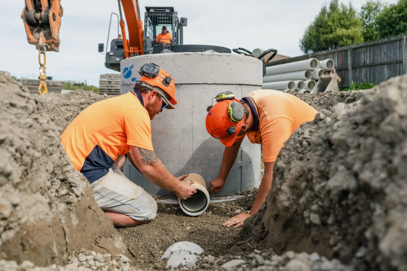 Two Maugers Contracting crew members laying pipe at a manhole