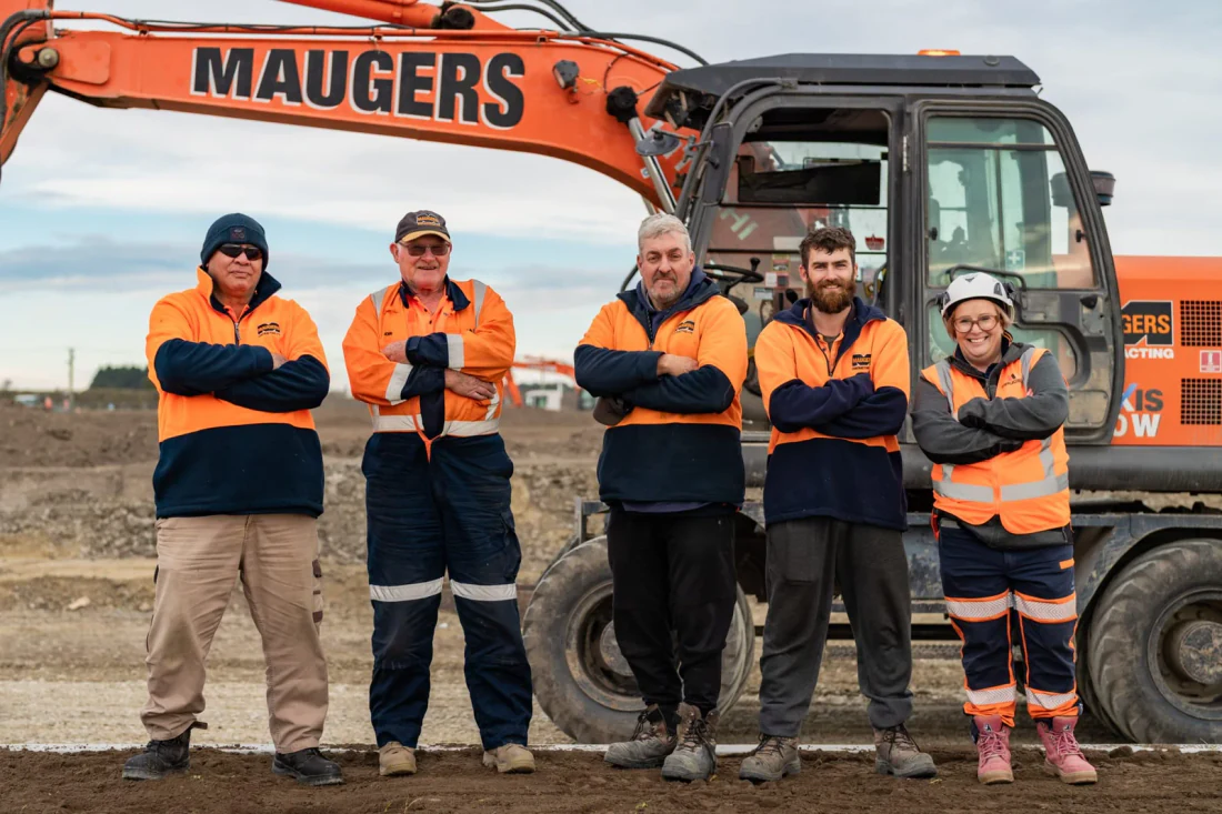 Maugers Contracting crew in hi-vis standing in front of one of their excavators