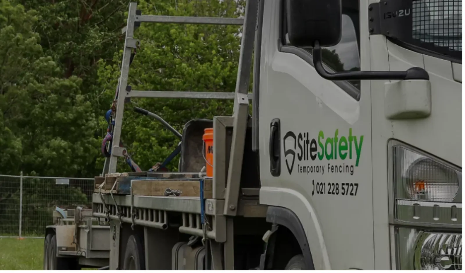 A Site Safety branded truck with a loaded deck, parked beside a line of temporary fencing, from the Site Safety website