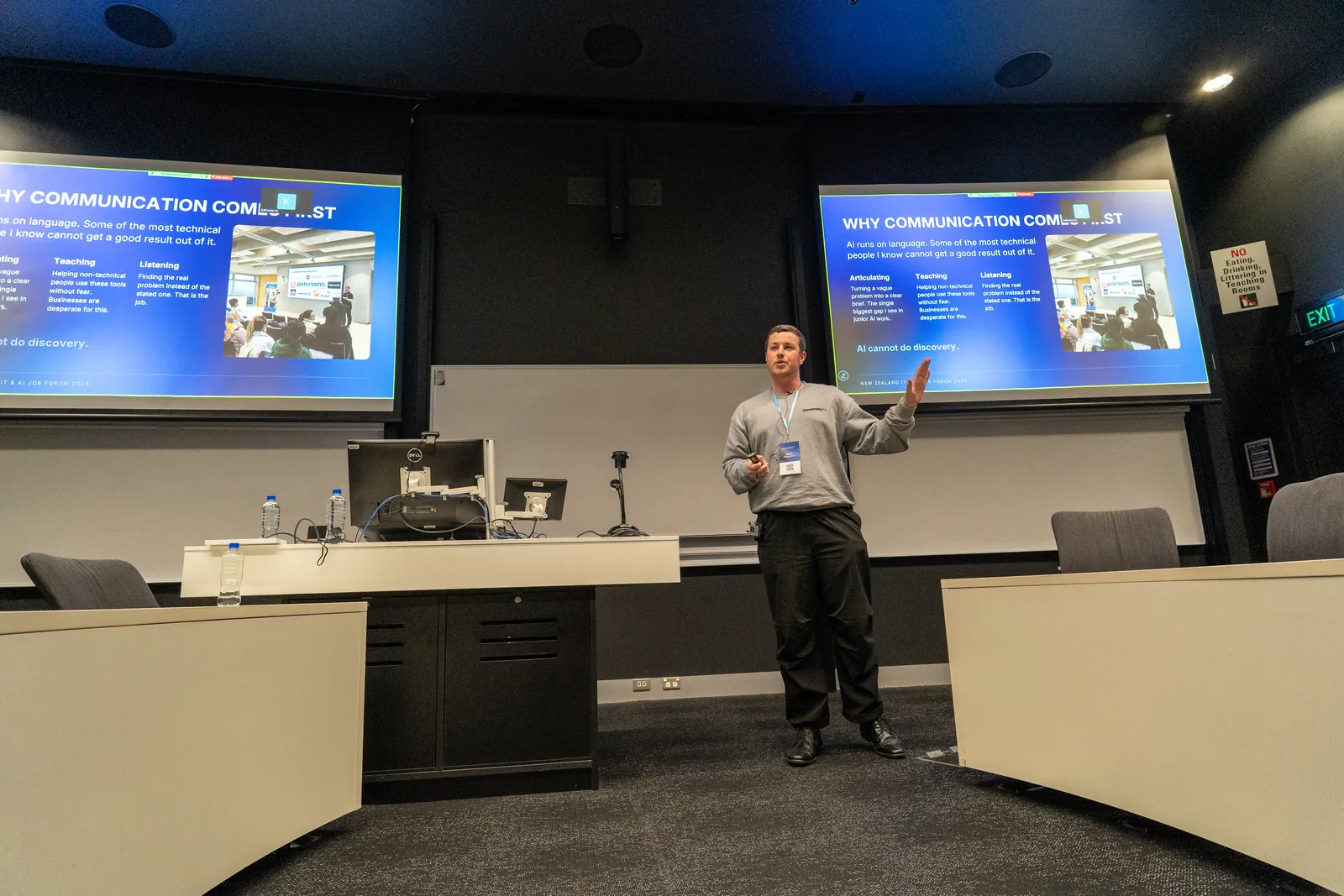 Blake Harkness presenting between twin screens in a University of Auckland lecture theatre at the NZ IT and AI Job Forum