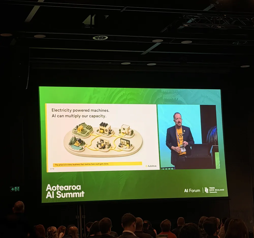 A keynote on the main screen at the Aotearoa AI Summit, audience in silhouette